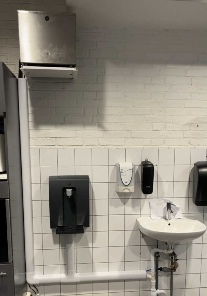 Håndvask med sæbedispensere og papirholder på væg