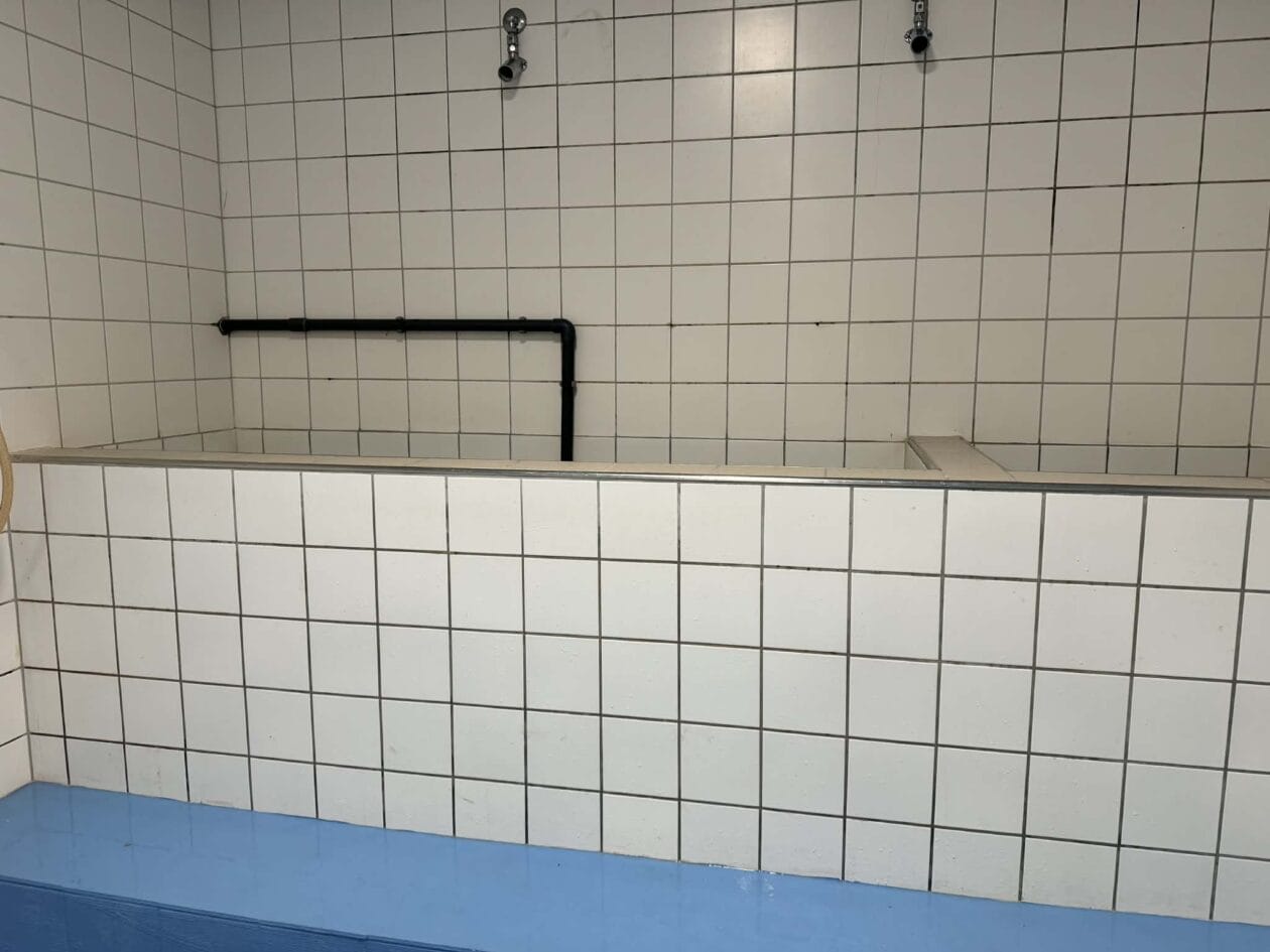 Flisebelagt bruseområde med rør og brusehoveder